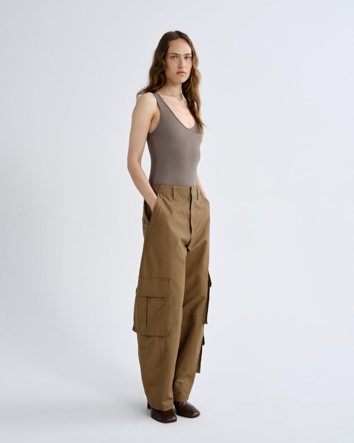 Woman wearing a brown tank top and cargo pants on a white background