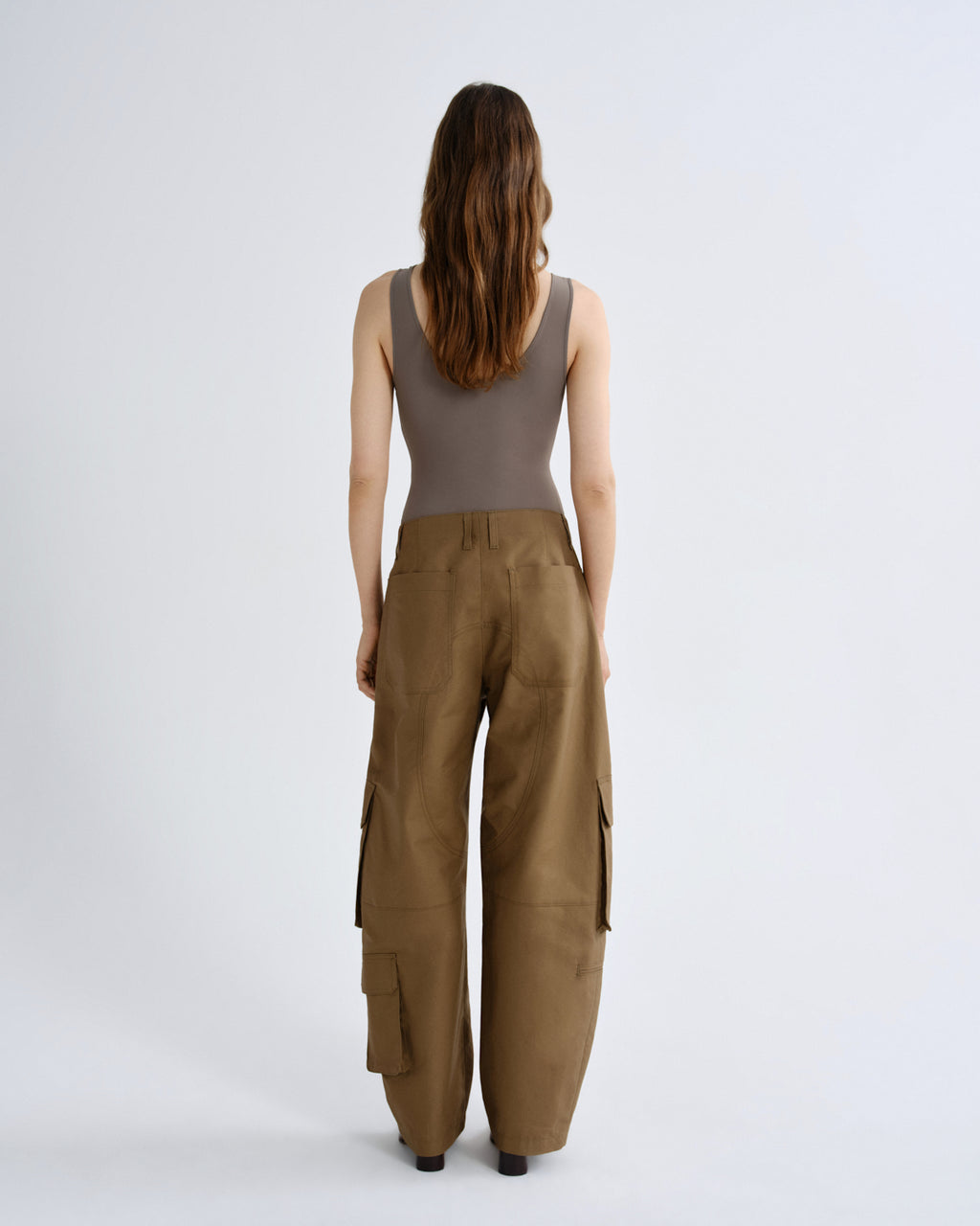 Woman wearing a sleeveless top and brown cargo pants on a white background