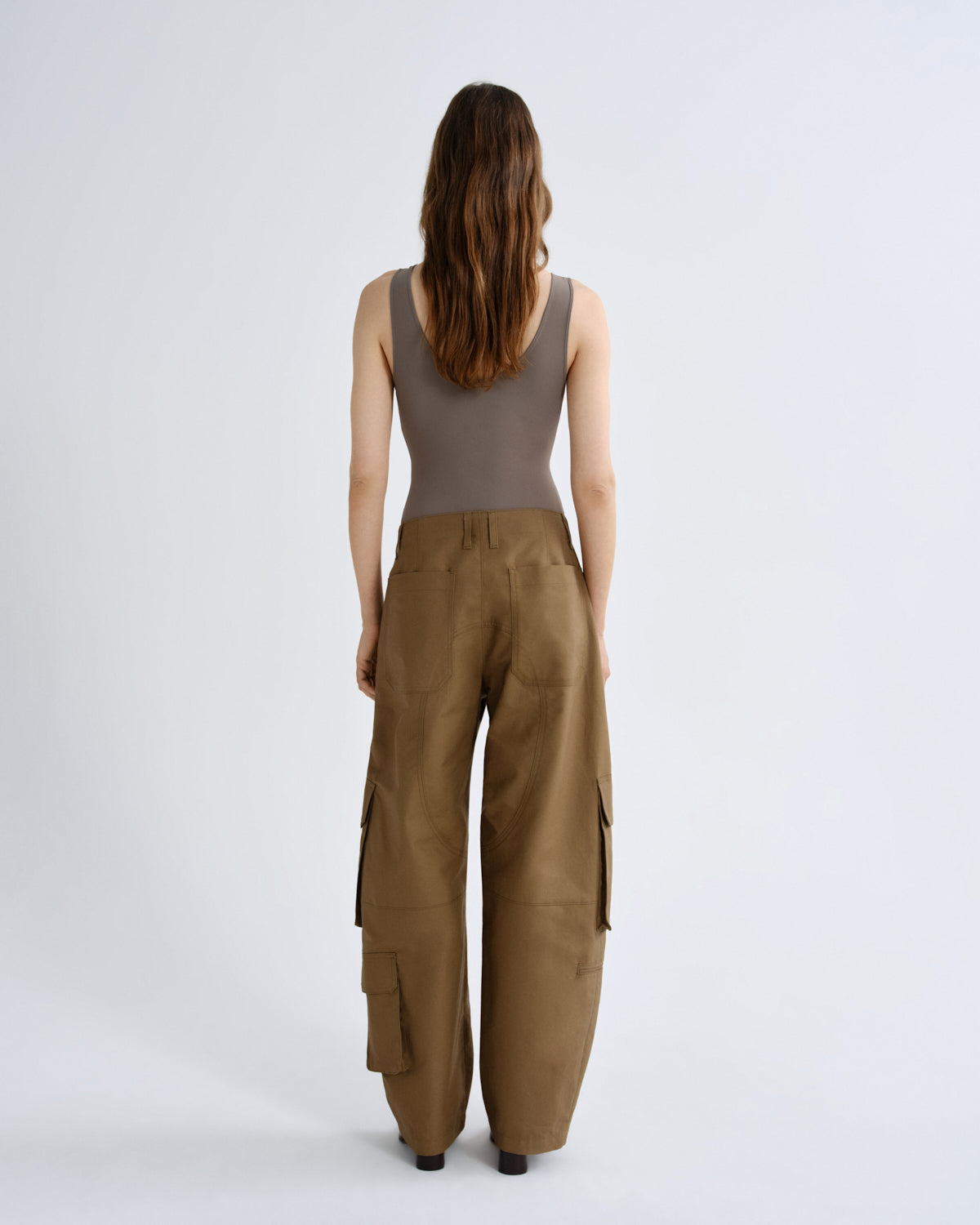 Woman wearing a sleeveless top and brown cargo pants on a white background
