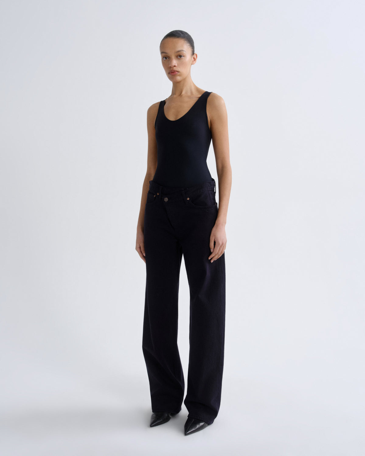 Person wearing a black sleeveless top and wide-leg pants on a white background