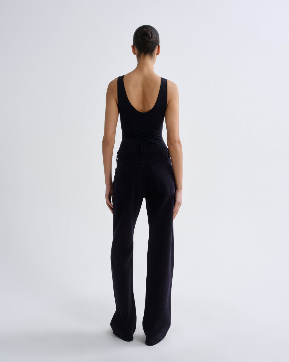 Person wearing a black sleeveless jumpsuit on a white background