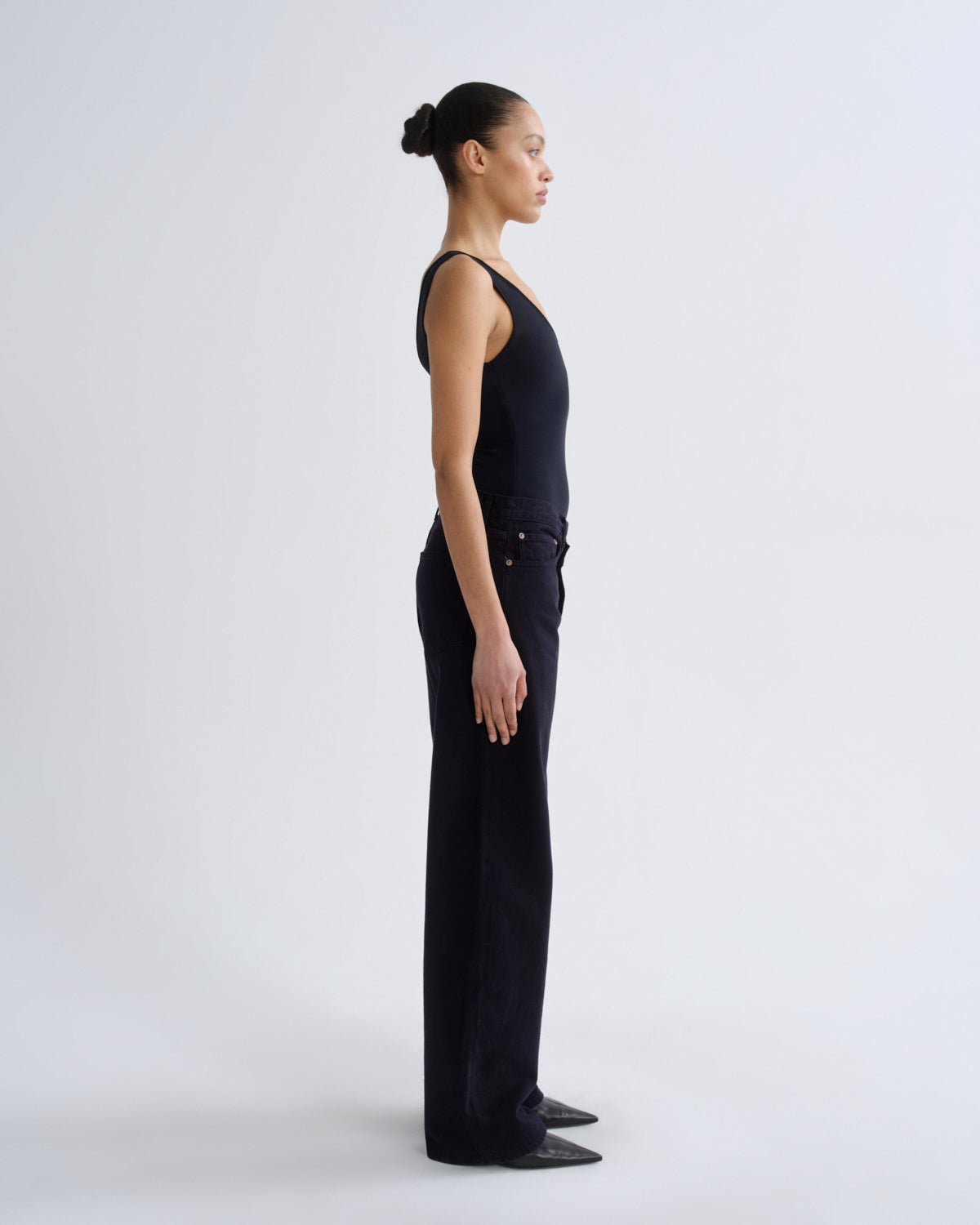 Person wearing a black sleeveless top and pants on a white background