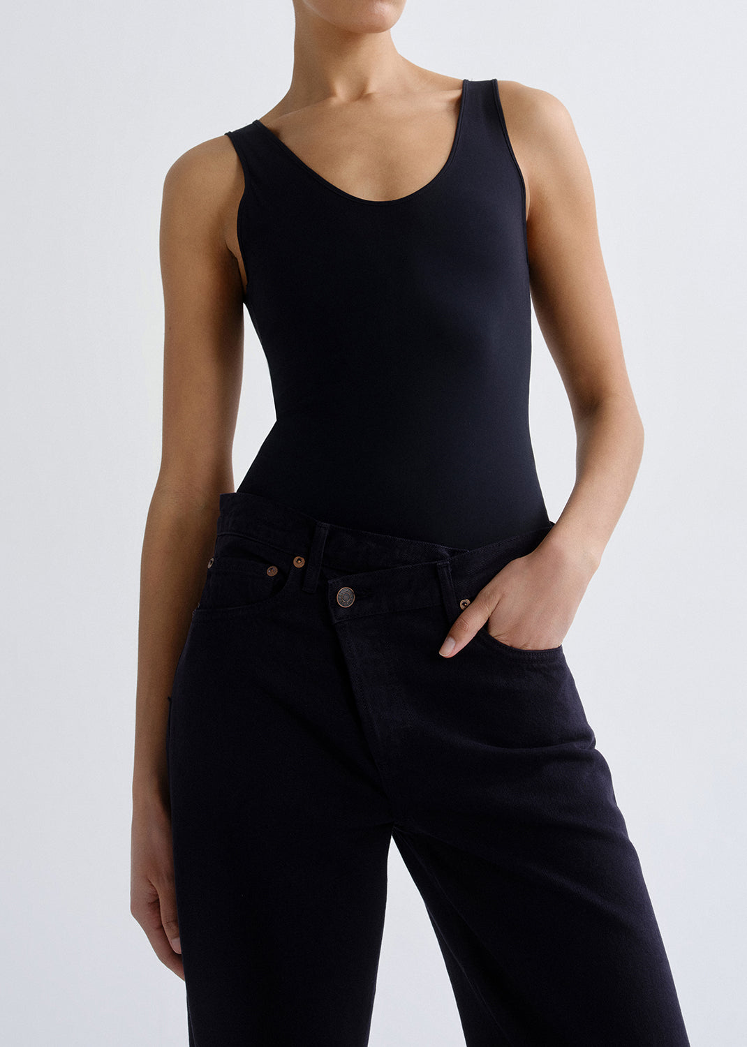 Person wearing a black tank top on a grey background.