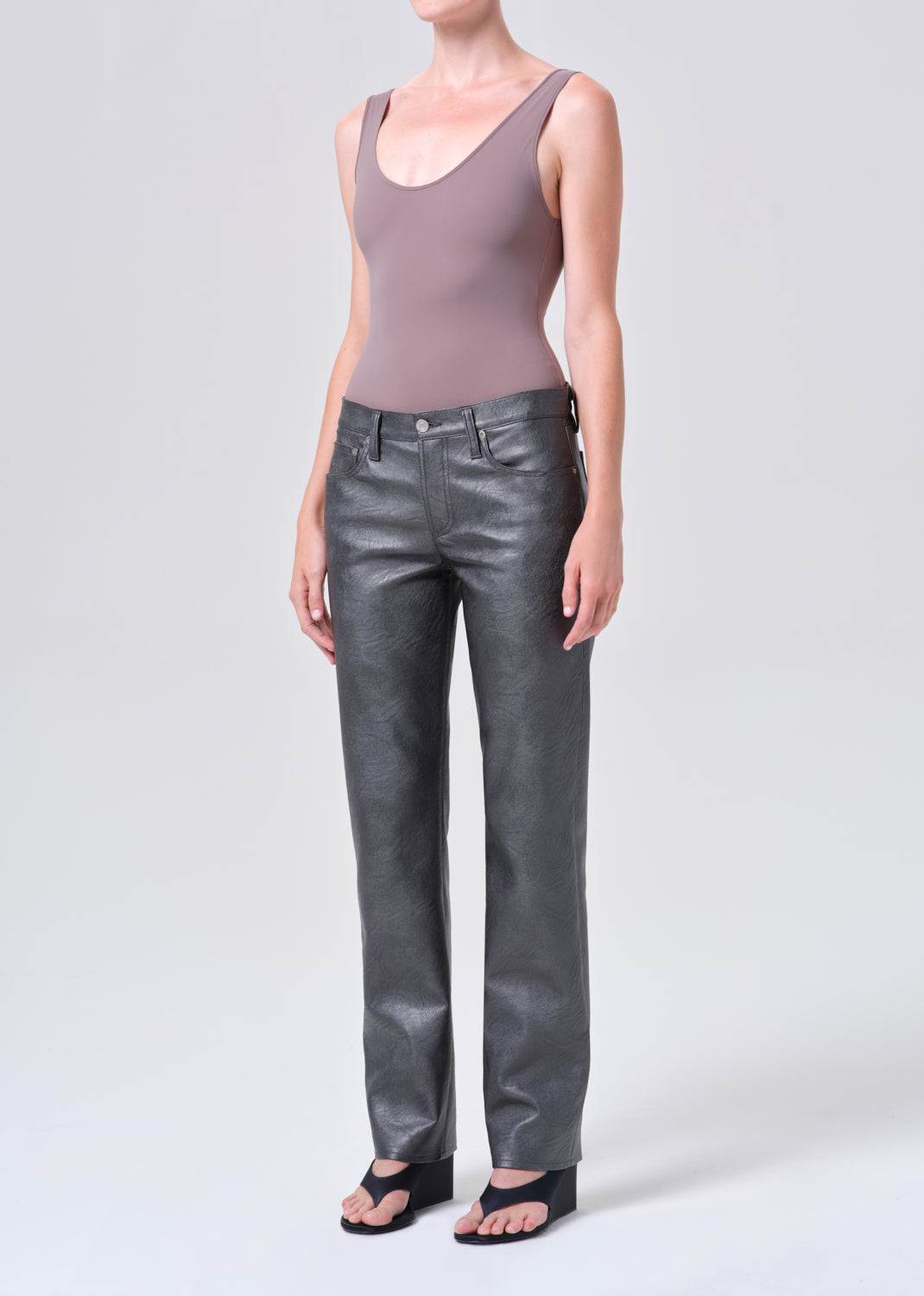 Person wearing a sleeveless mauve top and gray leather pants on a white background