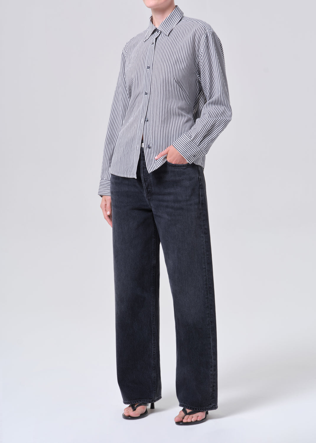 Person wearing a checkered shirt and dark pants on a white background