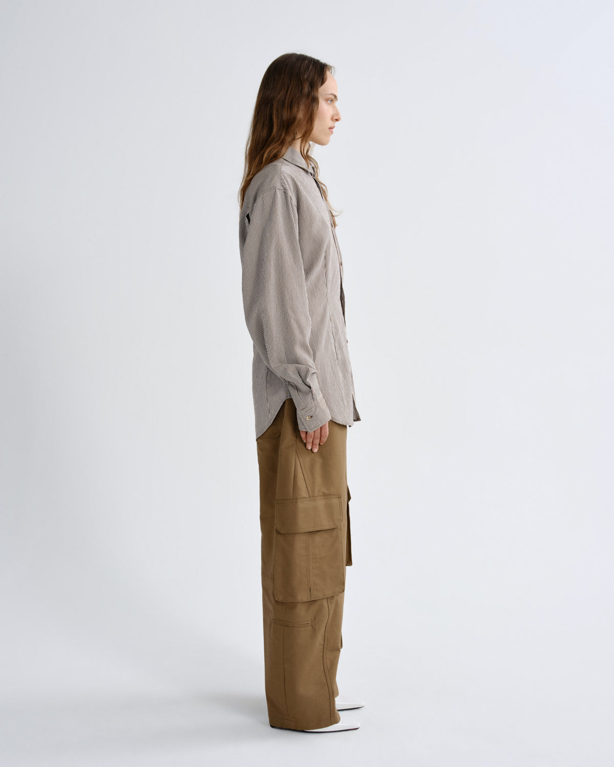 Woman wearing a light gray shirt and beige cargo pants on a white background