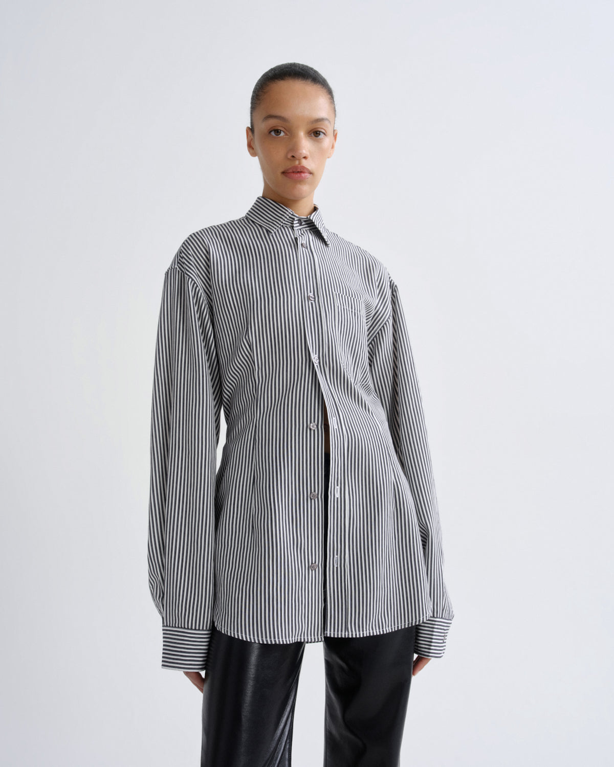 Person wearing a black and white striped shirt on a light gray background