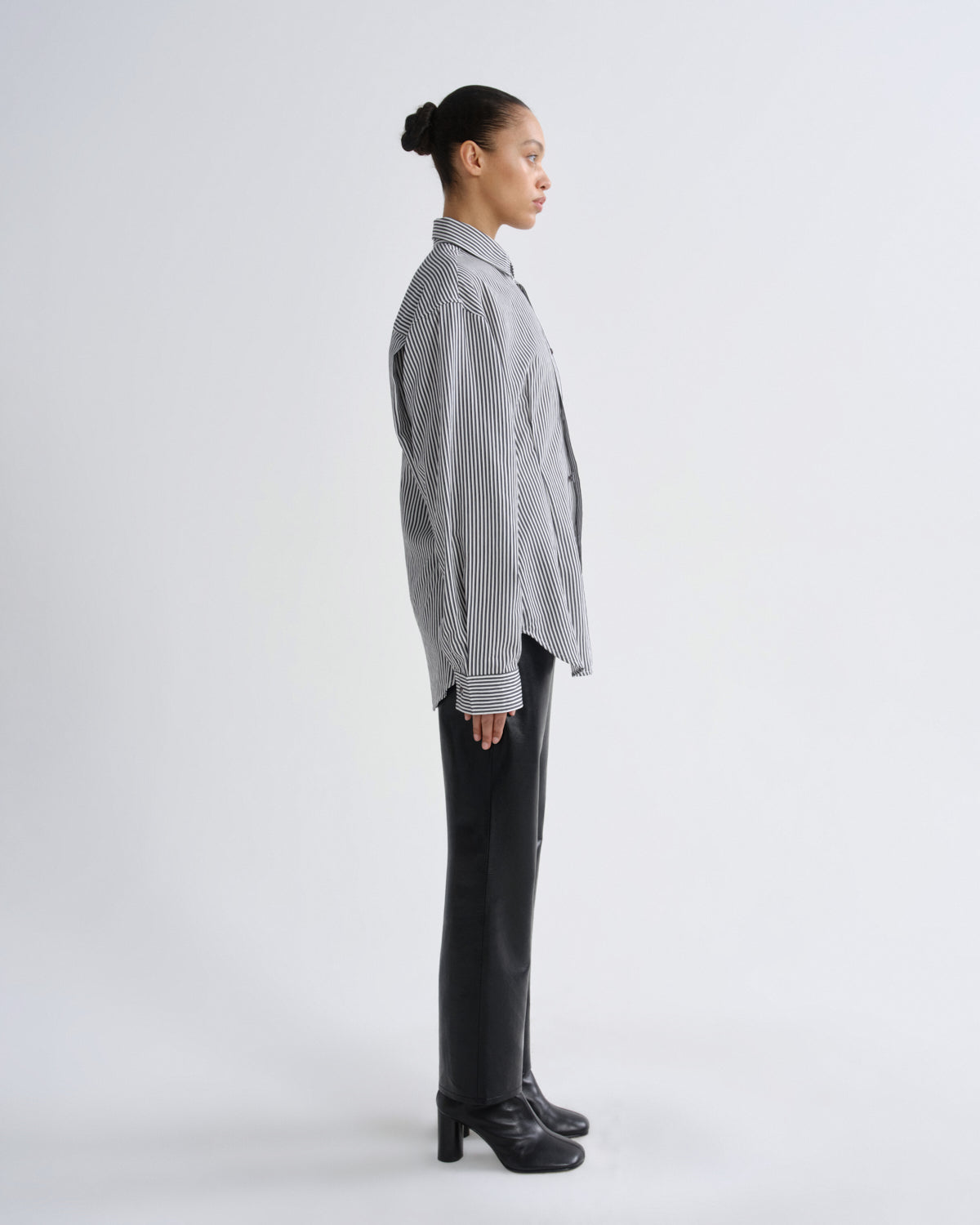 Person wearing a gray sweater and black pants on a white background