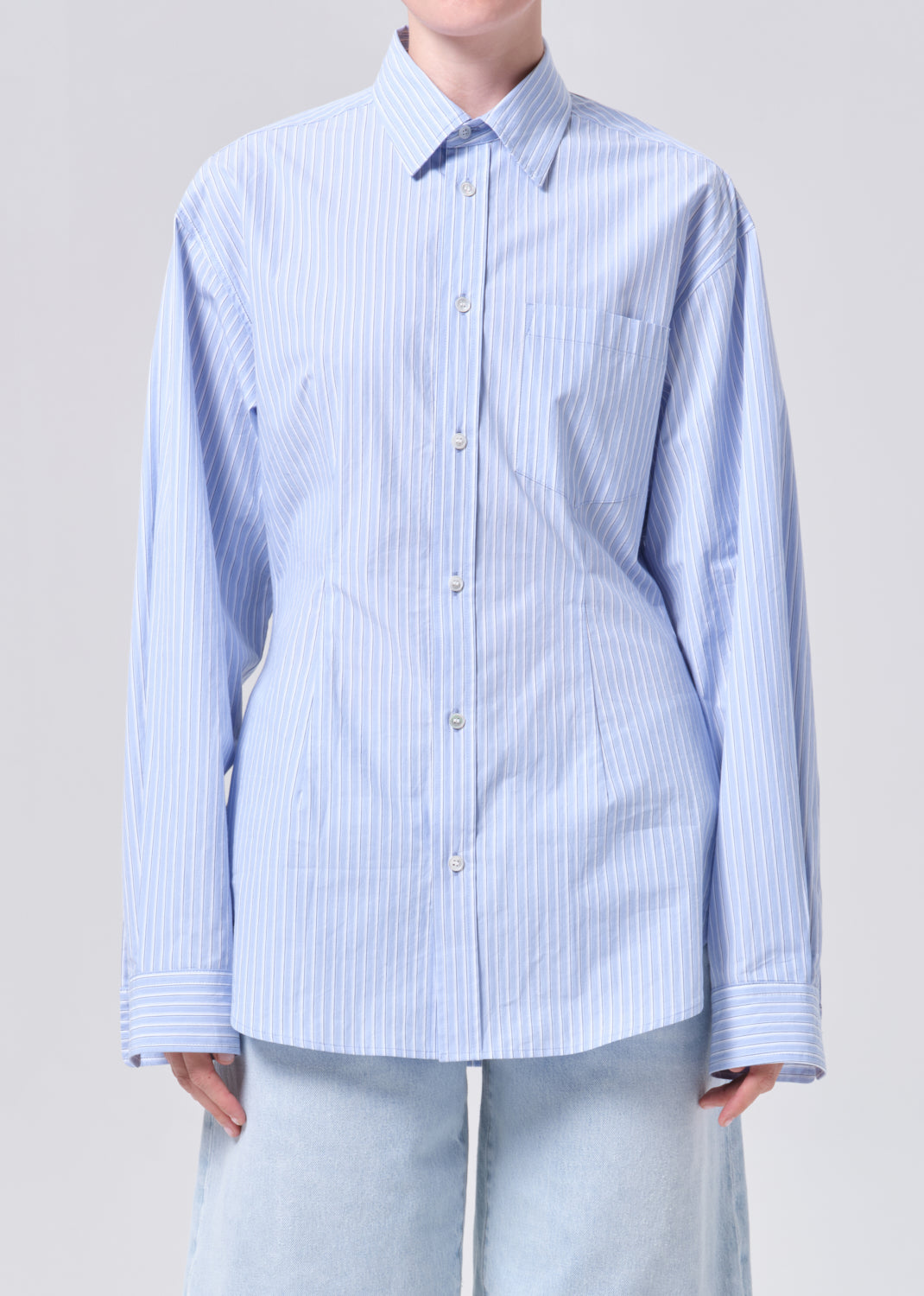 Person wearing a light blue and white striped shirt on a gray background