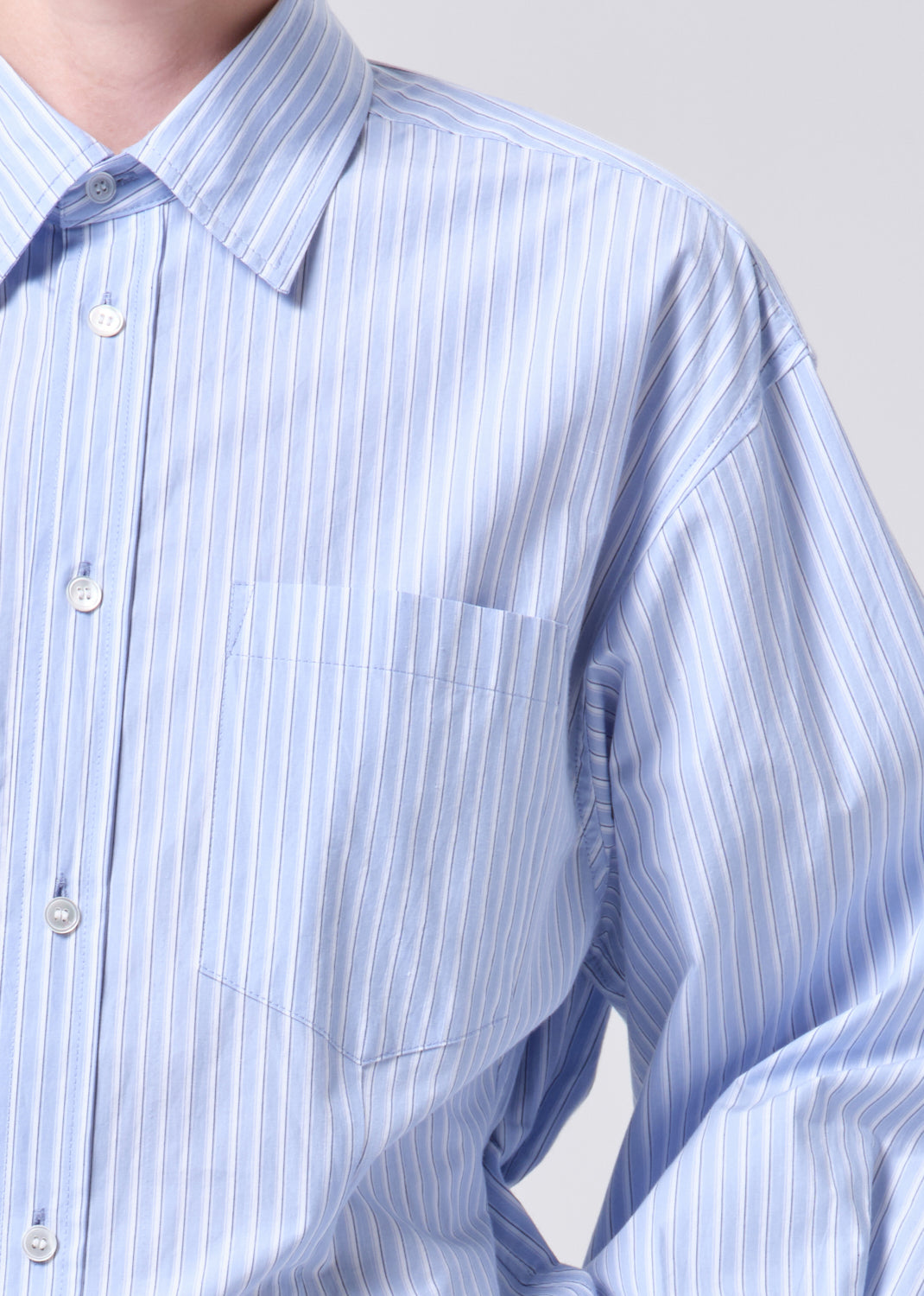 Close-up of a blue and white striped shirt with a pocket on a light gray background