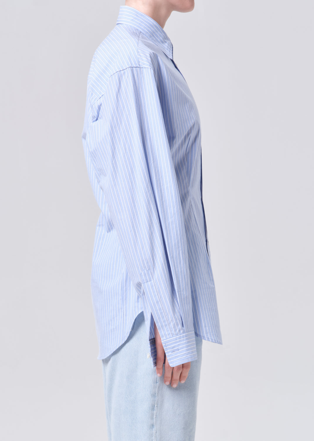 Person wearing a light blue striped shirt on a plain background