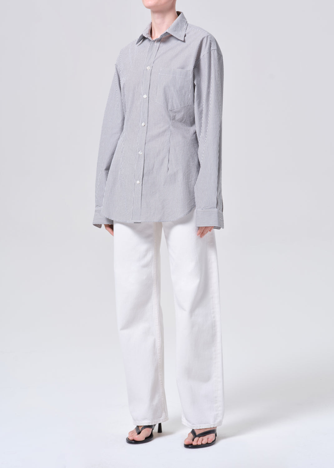 Person wearing a gray checkered shirt and white pants on a white background