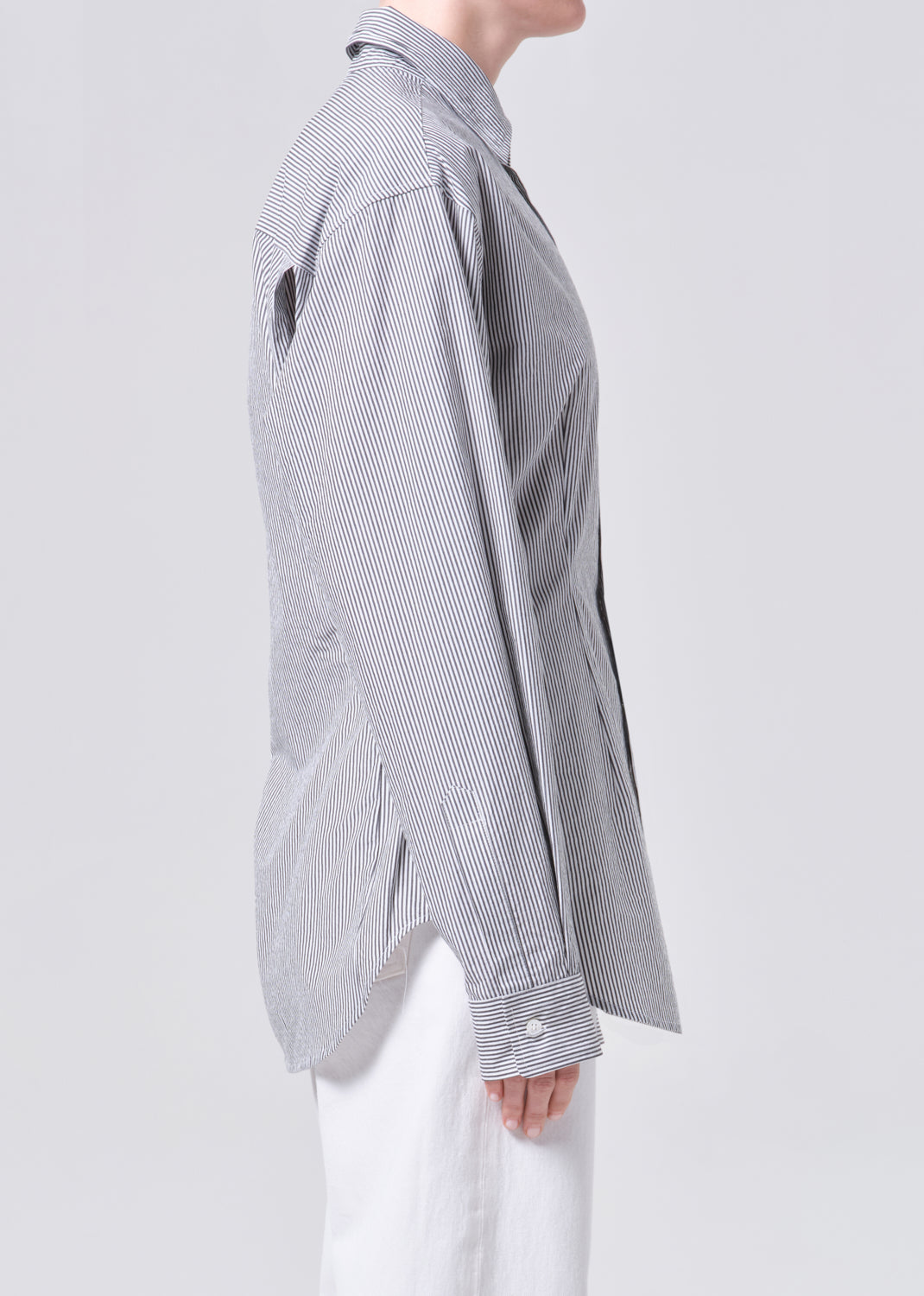 Person wearing a gray and white striped shirt on a light gray background