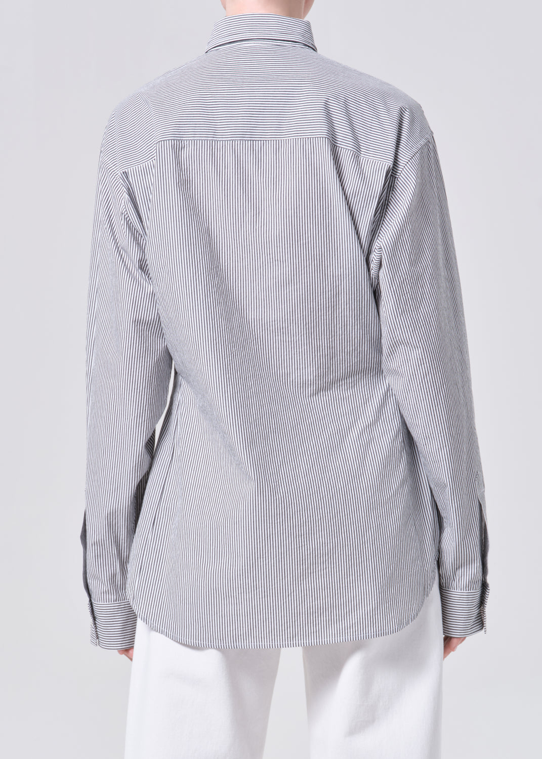 Back view of a person wearing a gray striped shirt on a white background