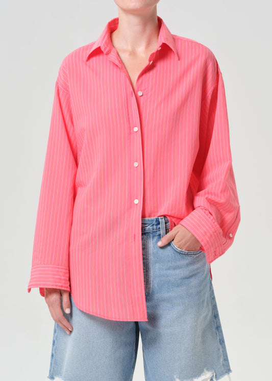 Person wearing a pink button-up shirt and light blue jeans on a gray background