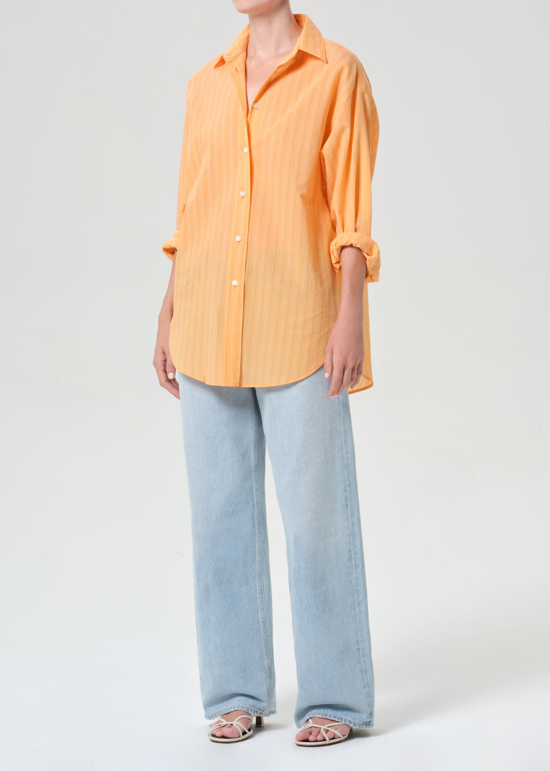 Person wearing an orange shirt and light blue jeans on a white background