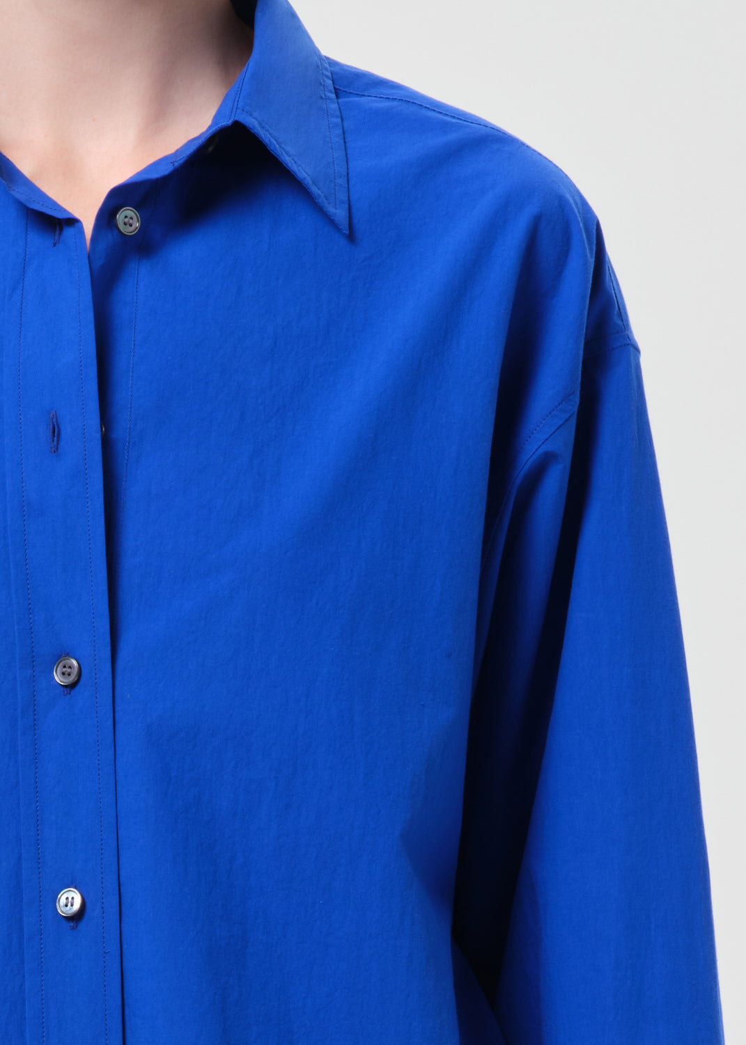 Close-up of a blue shirt with buttons on a plain background