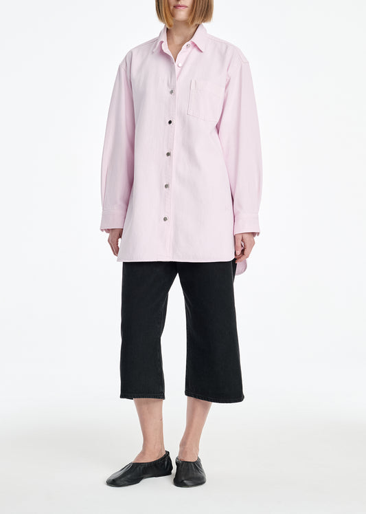 Person wearing a light pink shirt and black pants on a white background