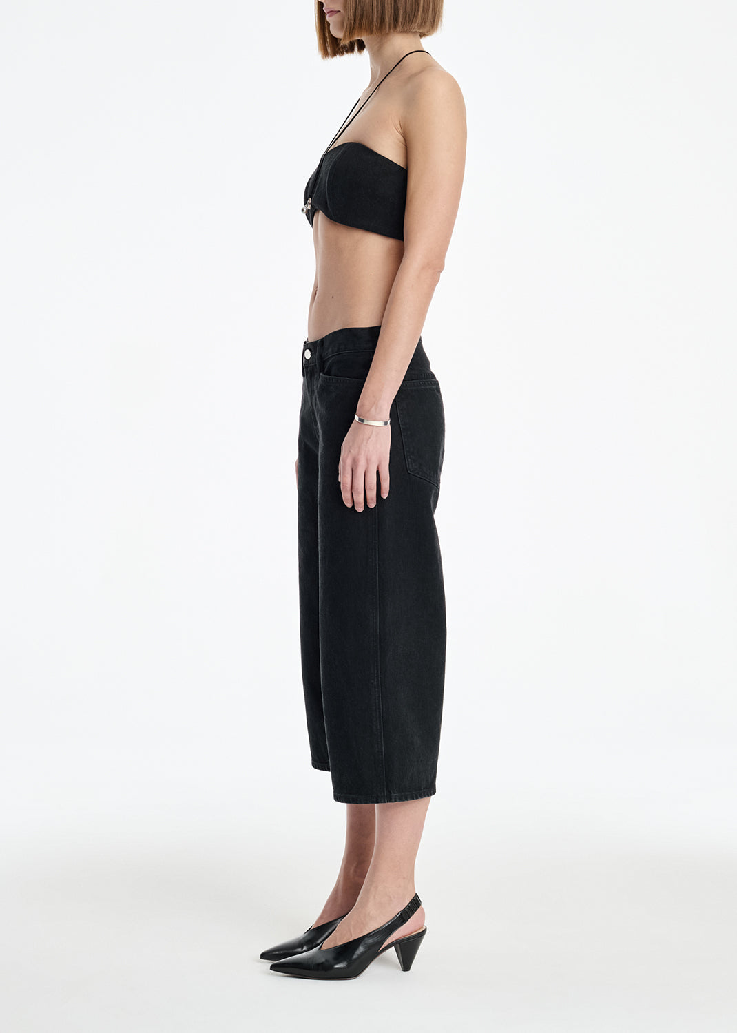 Person wearing a black strapless top and black high-waisted pants on a white background