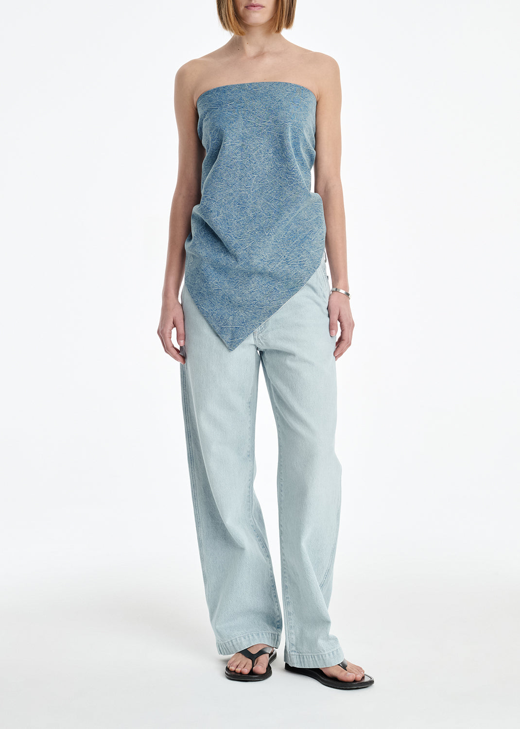 Woman wearing a strapless top and light-colored pants on a white background