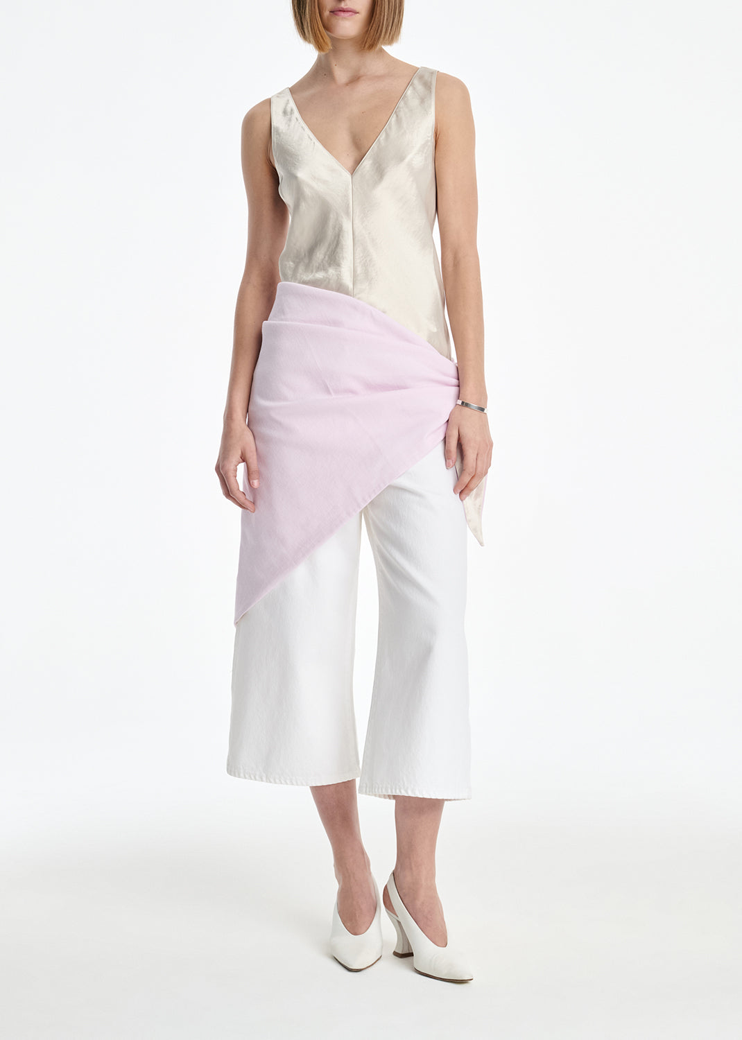 Woman wearing a sleeveless top and pink and white skirt on a white background