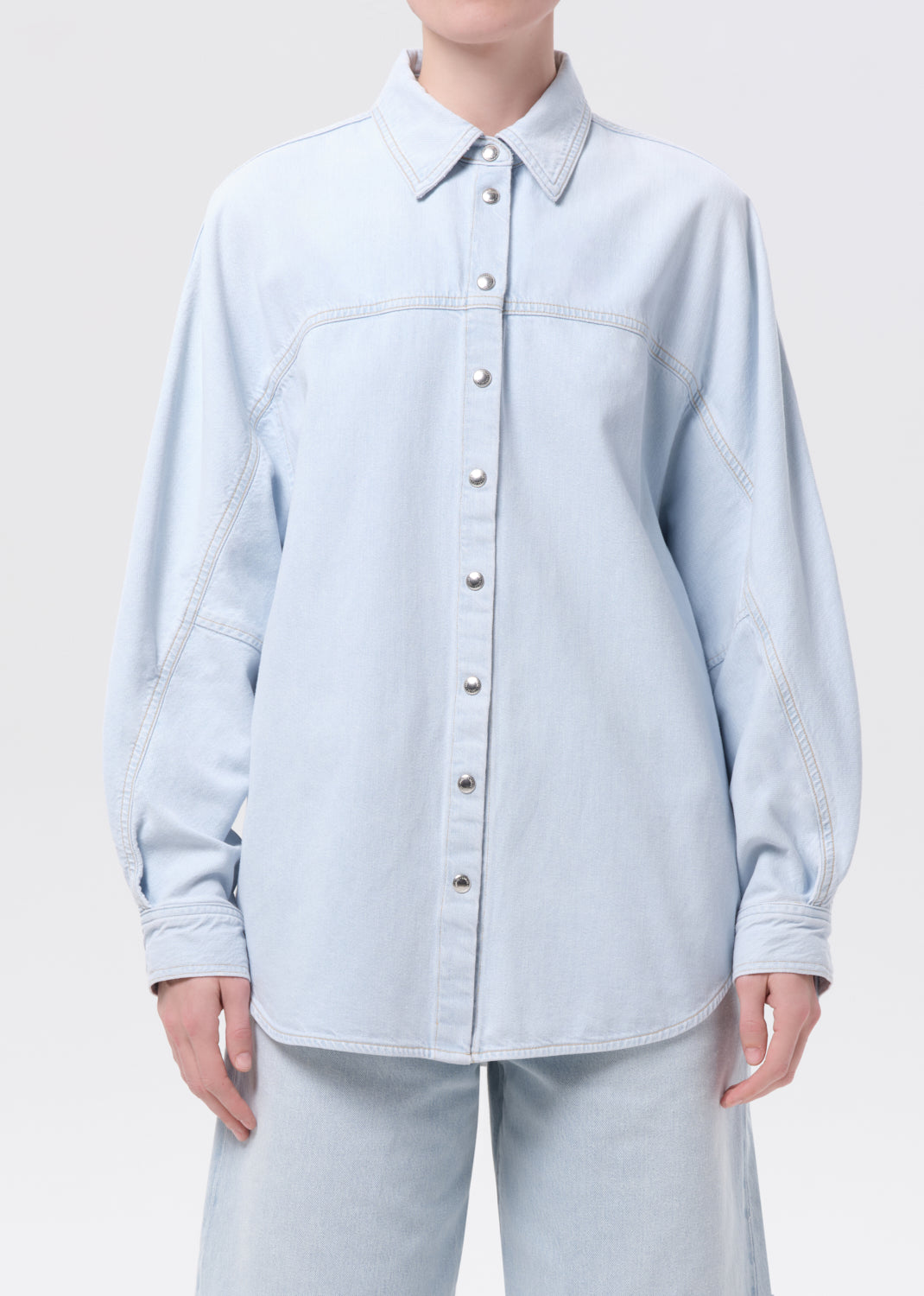 Light blue denim shirt worn by a person on a white background