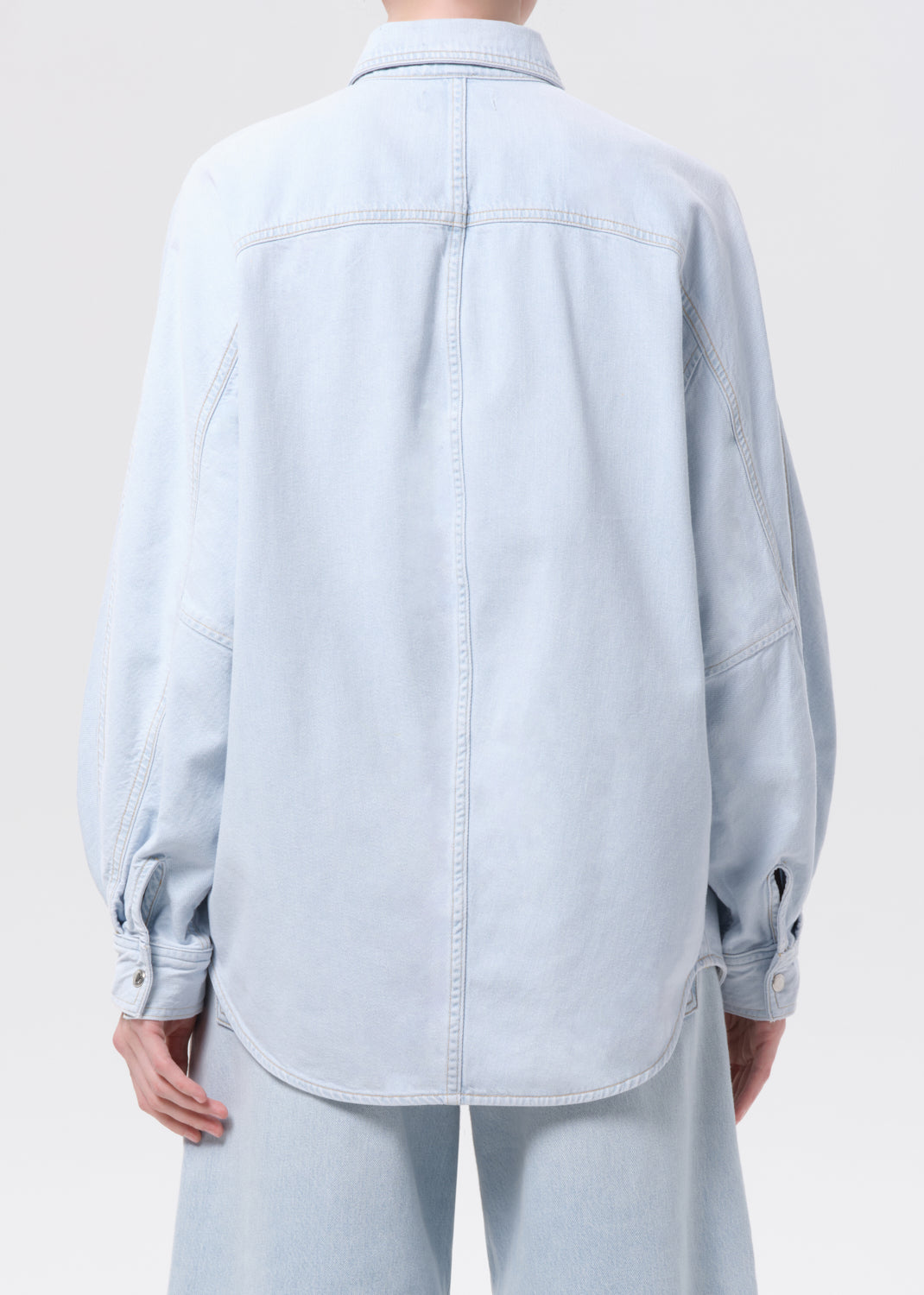 Light blue denim shirt worn by a person on a white background