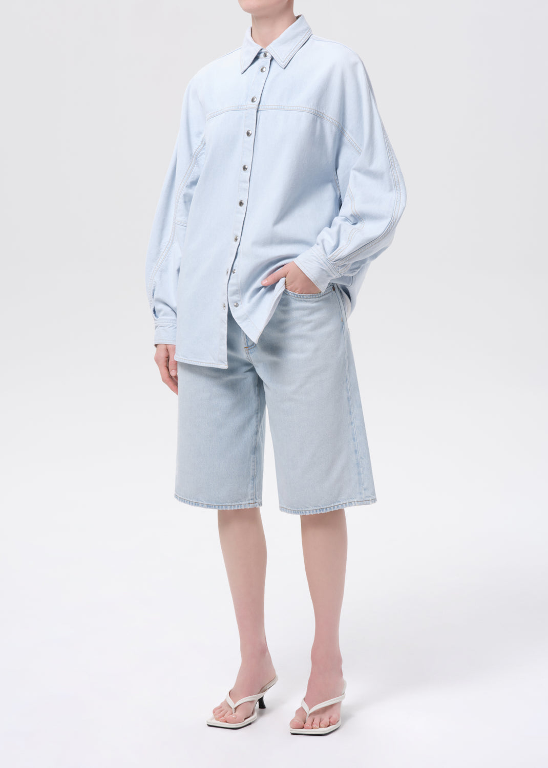 Person wearing a light blue shirt and shorts on a white background