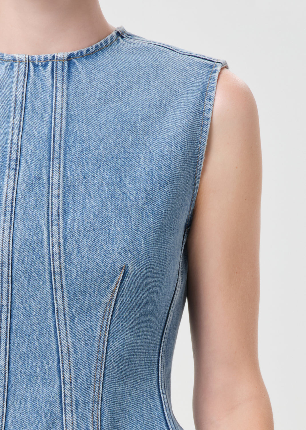 Close-up of a light blue denim sleeveless top on a white background