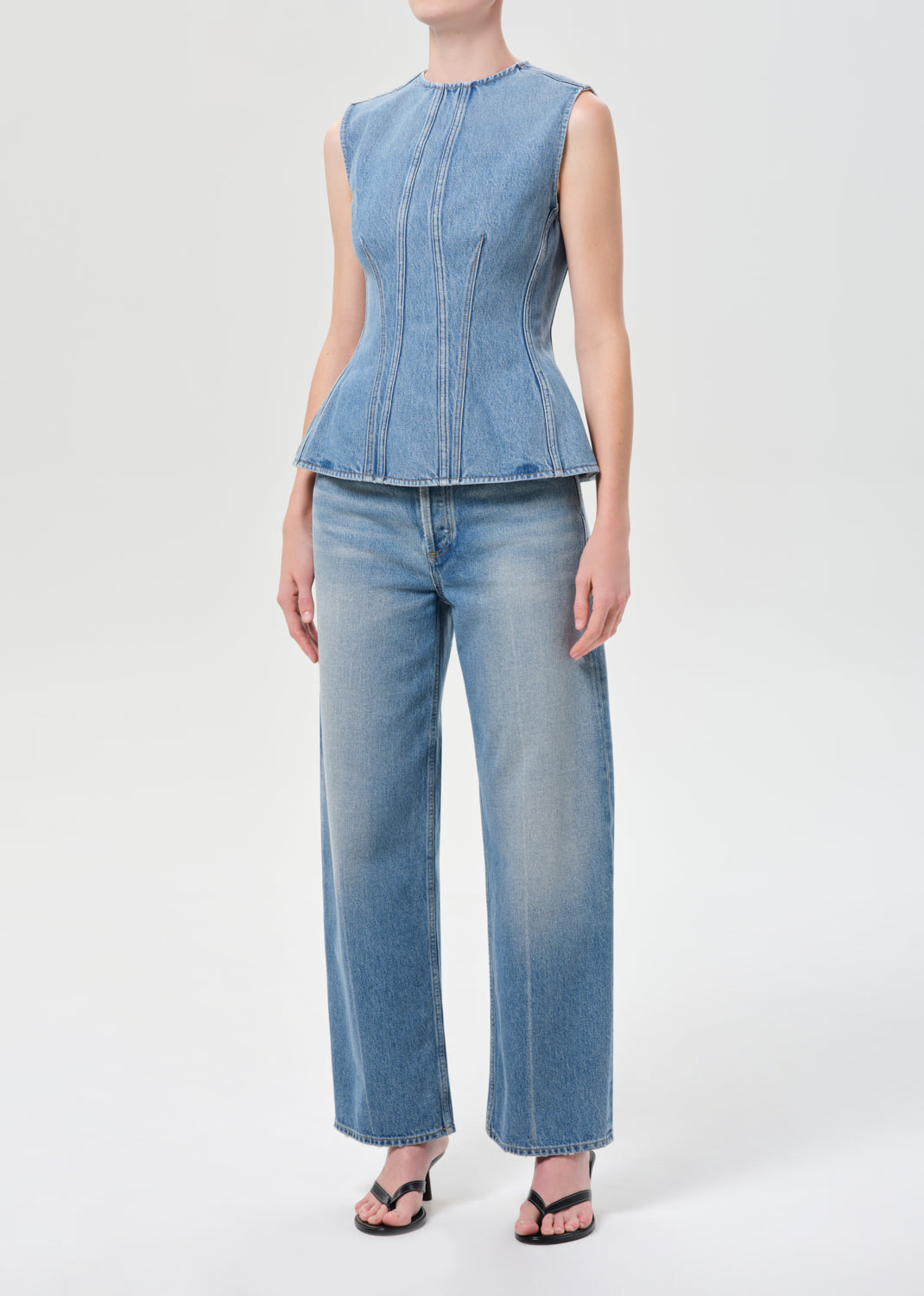 Person wearing a denim top and jeans on a white background