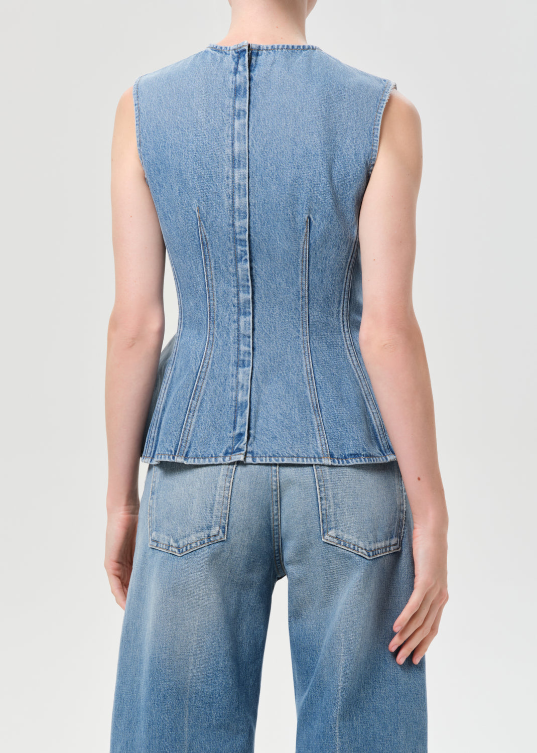 Denim sleeveless top and jeans on a plain background