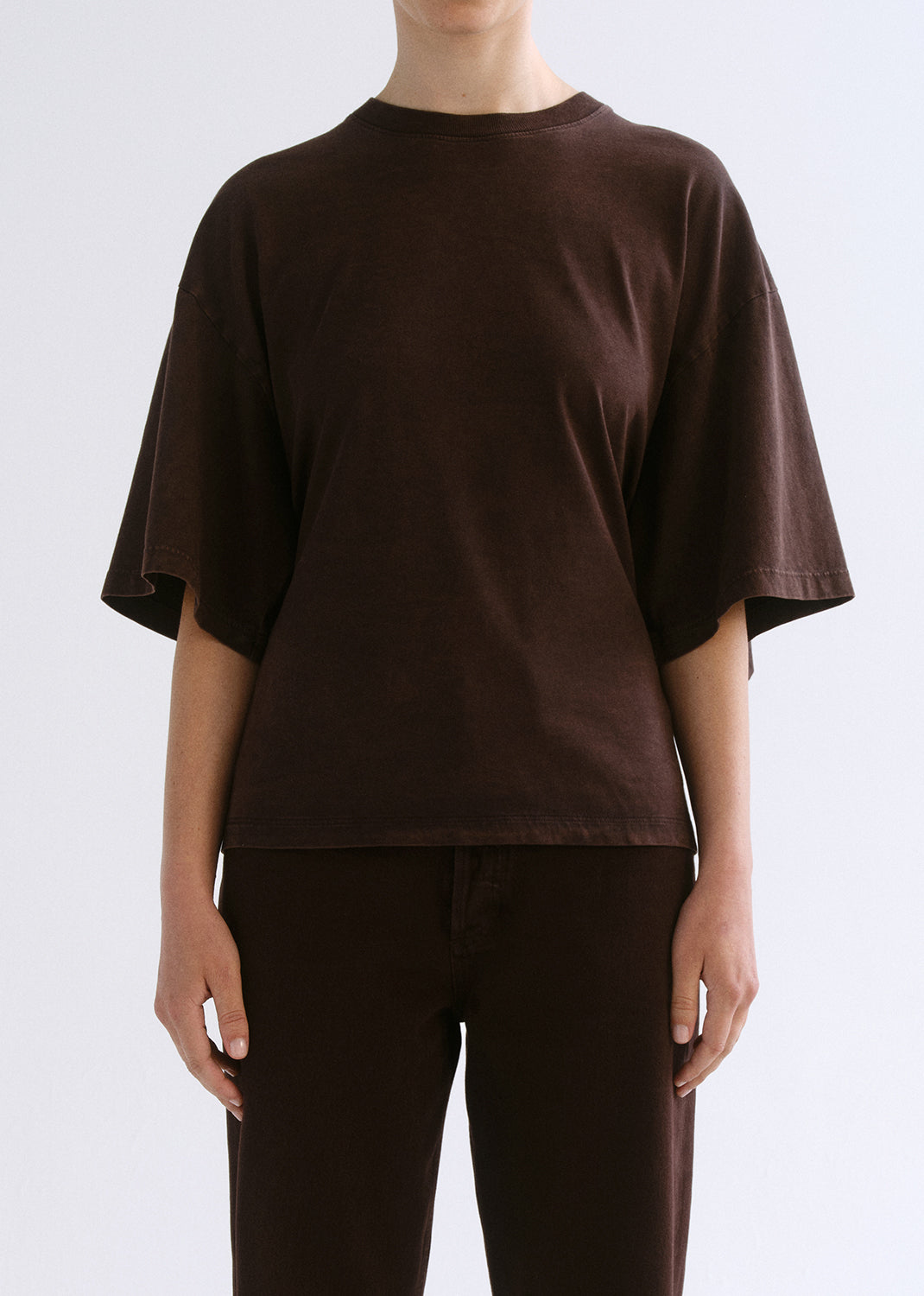 Person wearing a brown shirt on a grey background