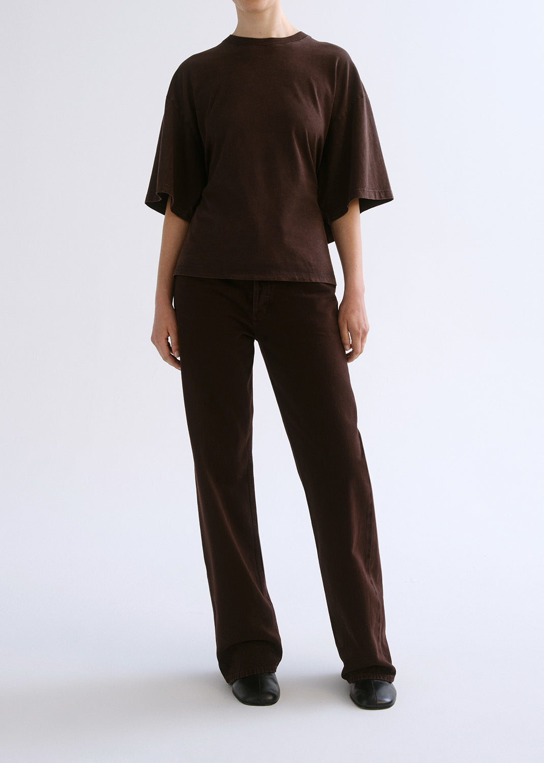 Person wearing a brown outfit on a grey background