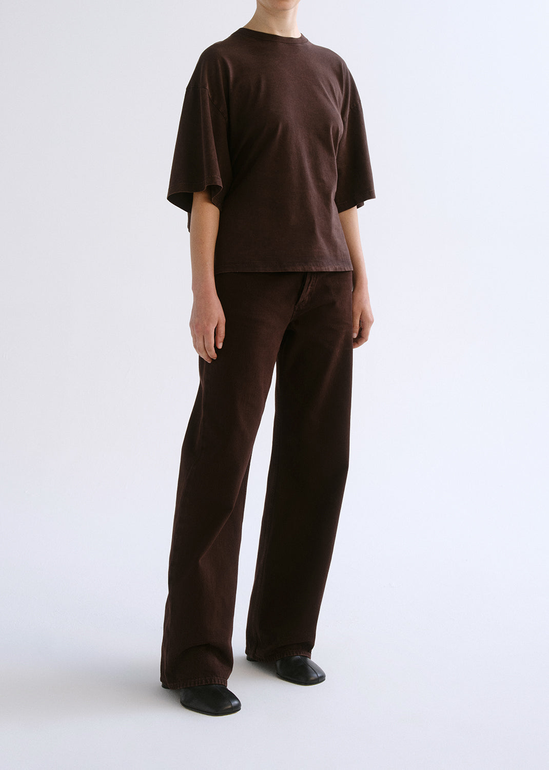 Person wearing a brown outfit on a grey background