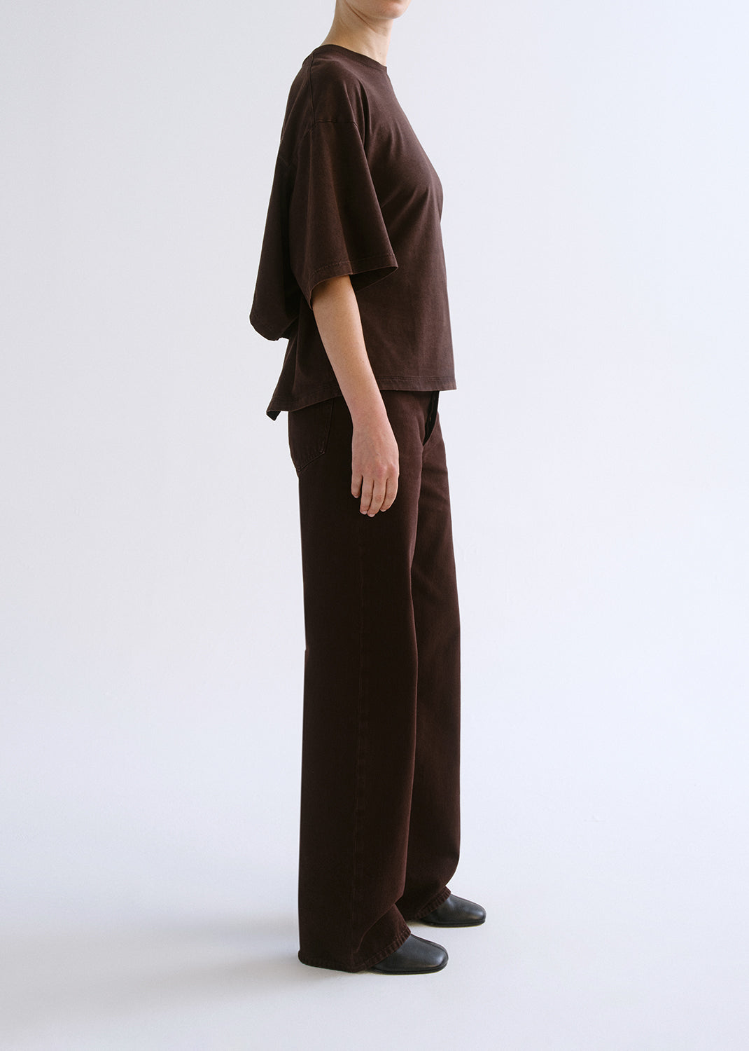 Person wearing a brown outfit on a grey background