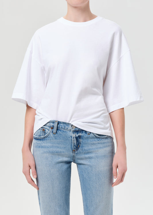 Person wearing a white t-shirt and light blue jeans on a plain background