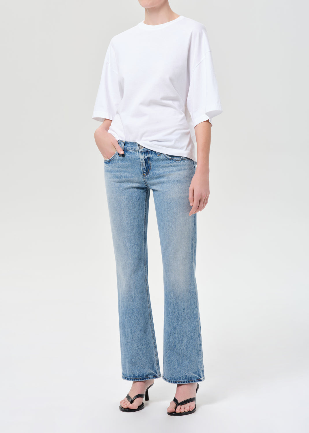 Person wearing a white t-shirt and light blue jeans on a white background