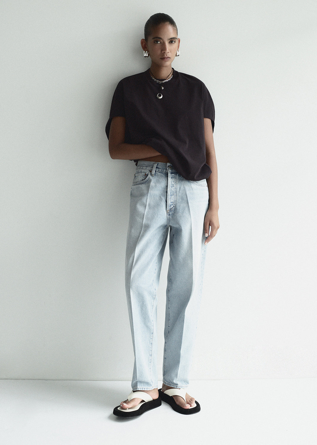 Person wearing a black t-shirt and light blue jeans against a white background
