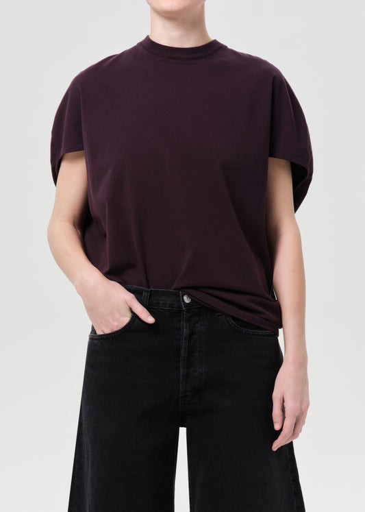 Person wearing a dark purple t-shirt and black pants on a light gray background