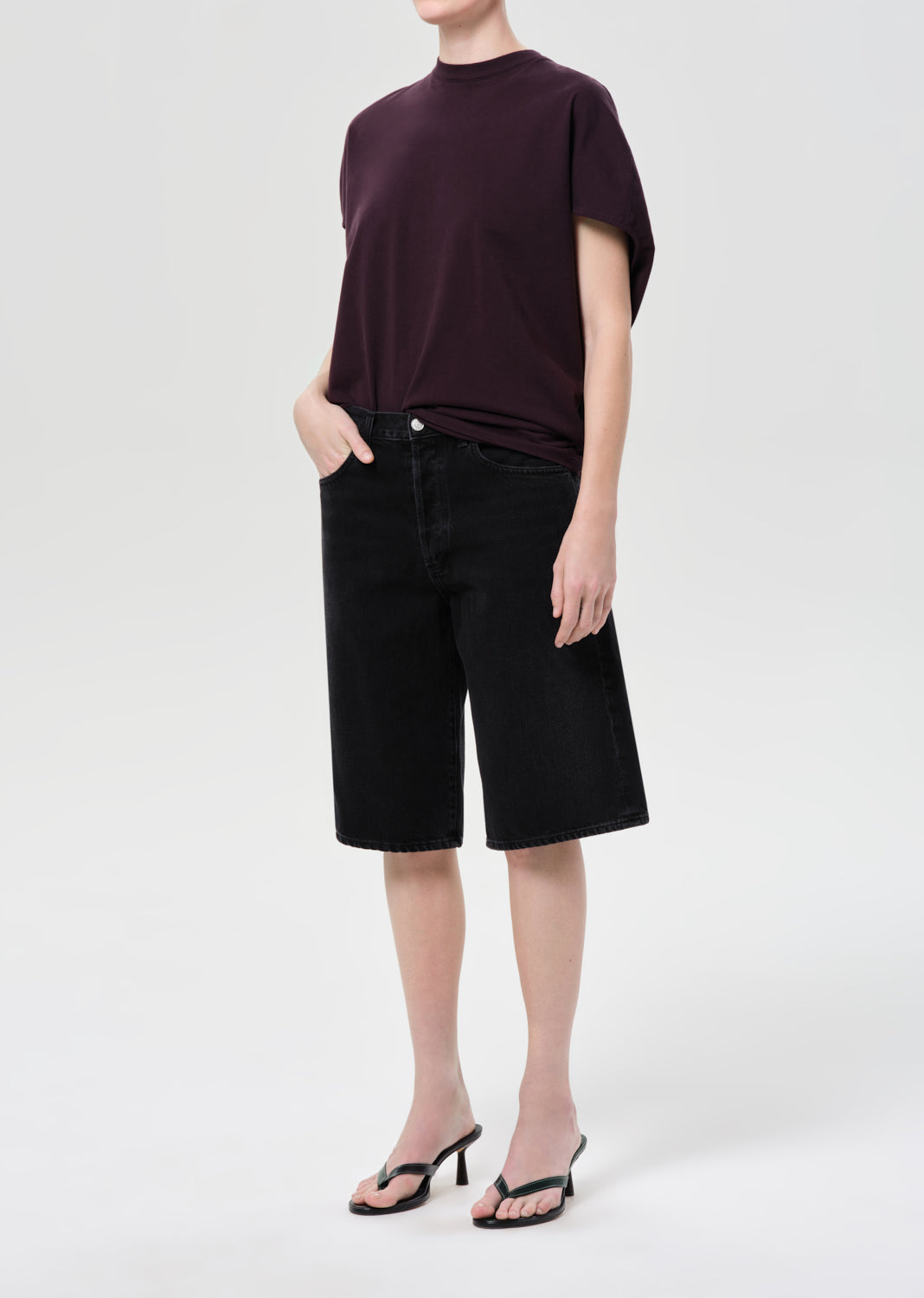 Person wearing a dark purple top and black shorts on a white background