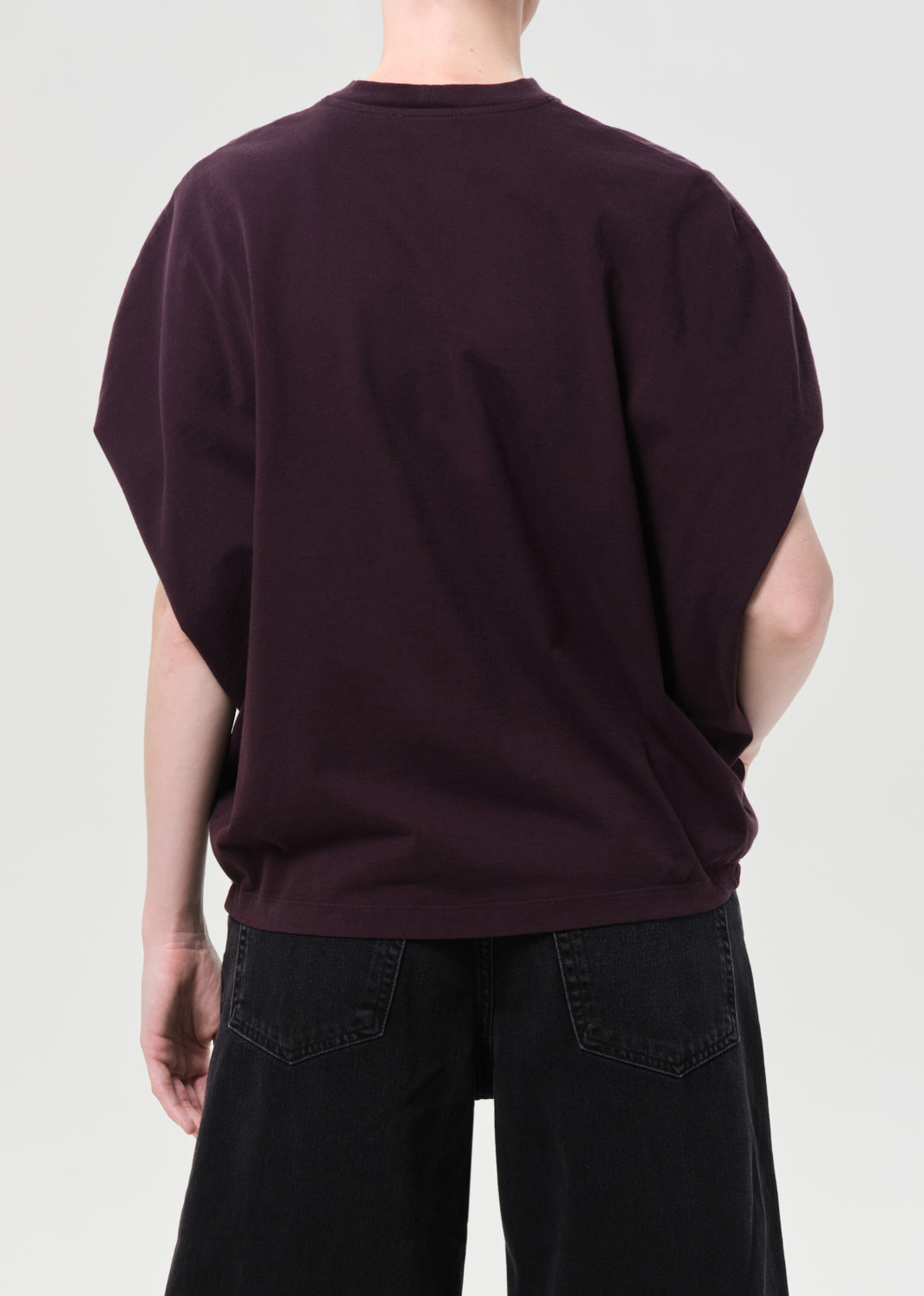 Person wearing a dark purple oversized t-shirt and black pants on a light gray background