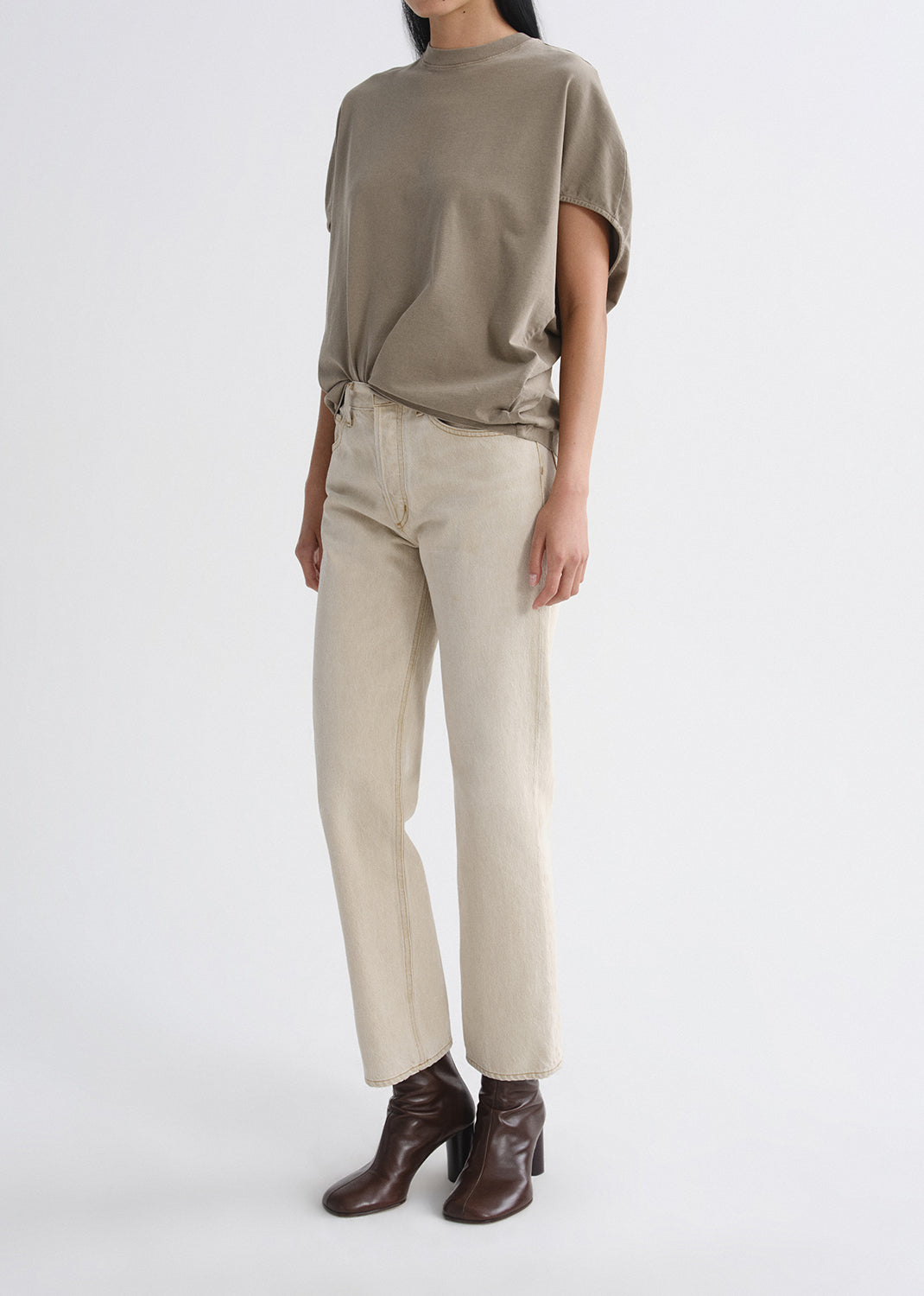 Person wearing a green top and beige pants on a grey background