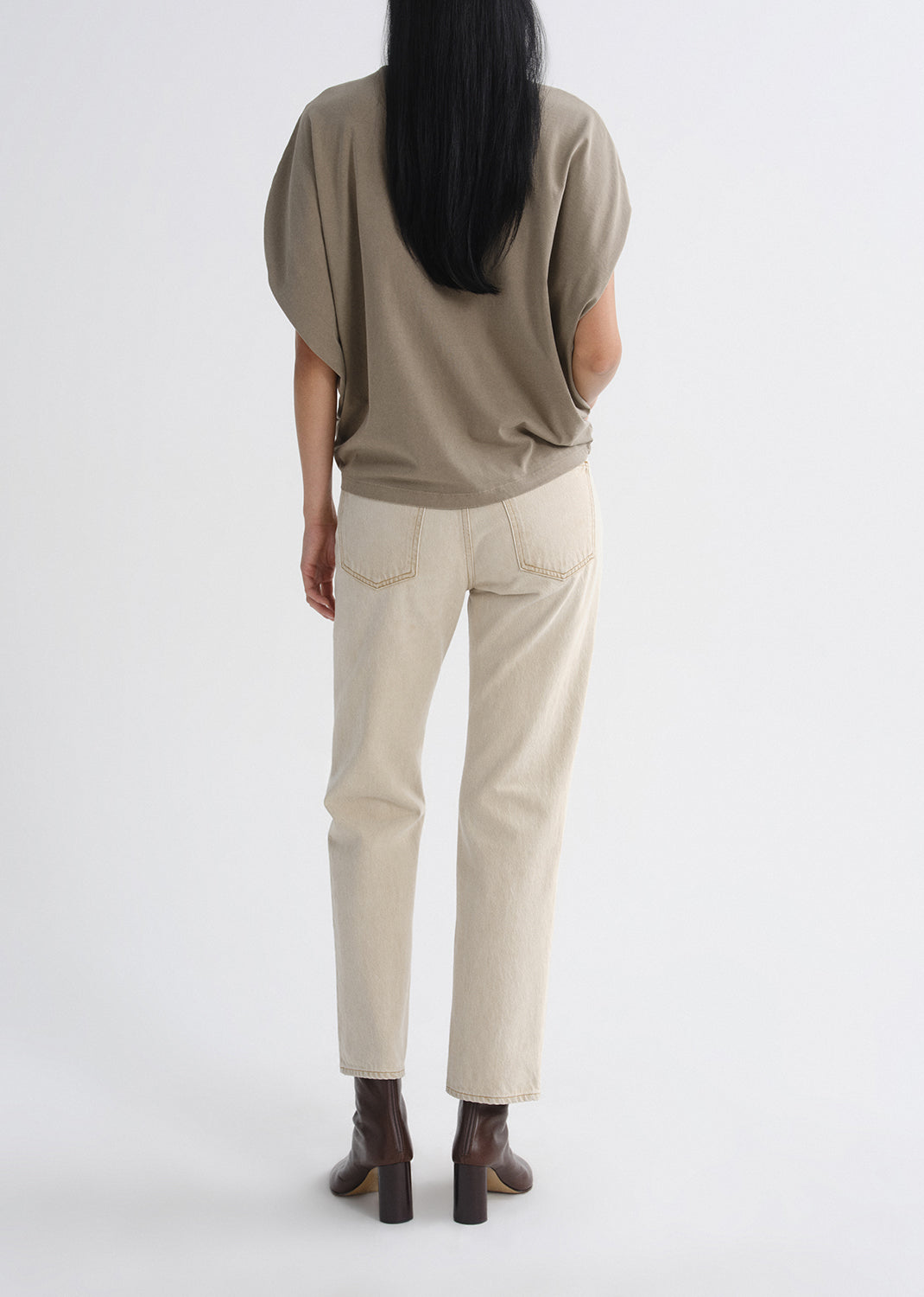 Person wearing a beige top and light-colored pants on a grey background