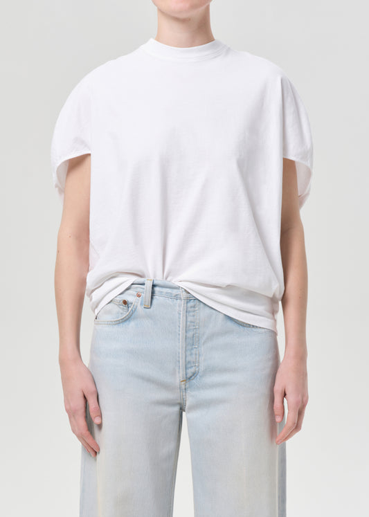 Person wearing a white t-shirt and light blue jeans on a plain background