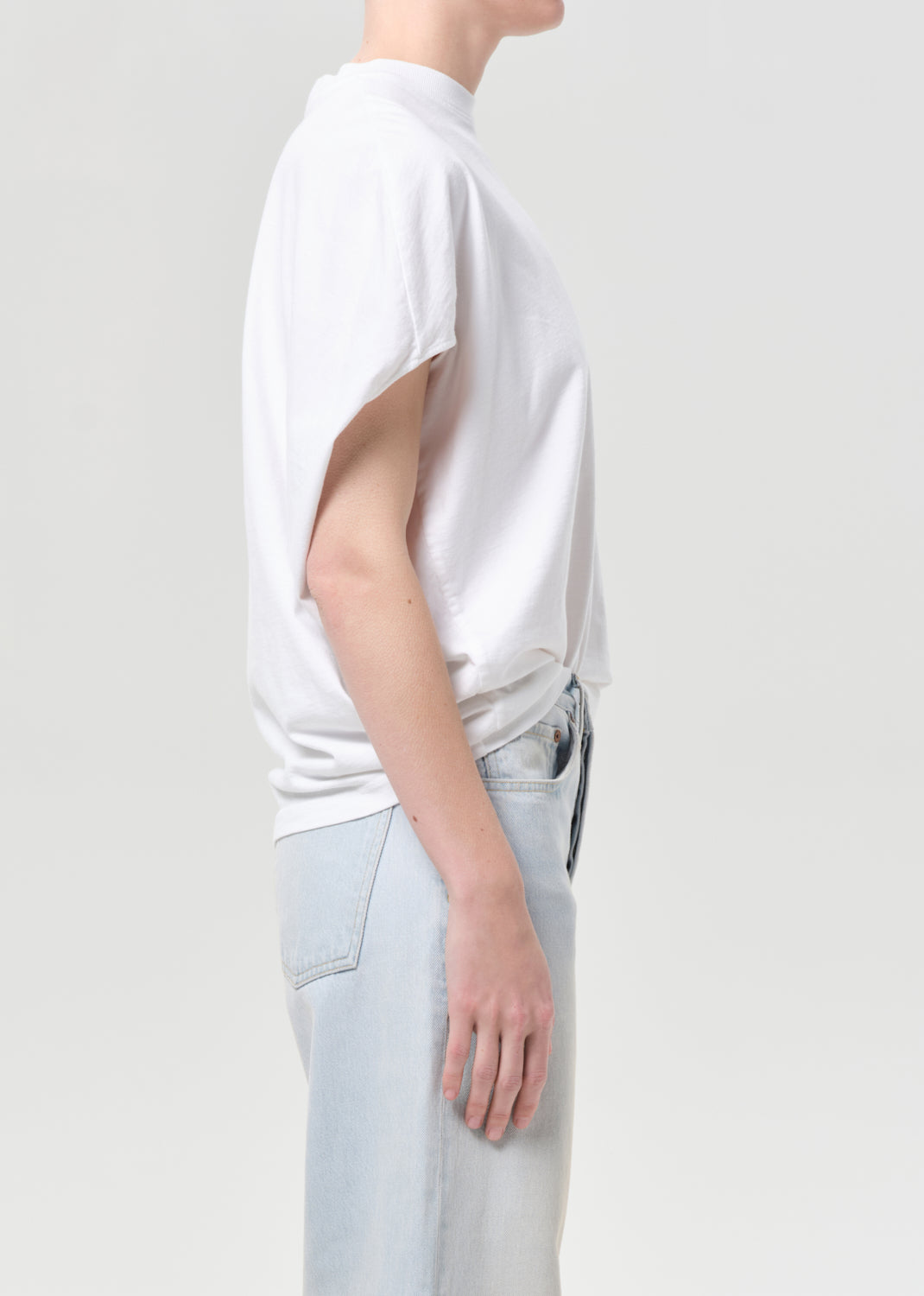 Person wearing a white t-shirt and light blue pants on a plain background