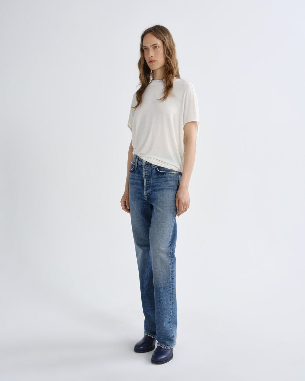 Woman wearing a white t-shirt and blue jeans on a white background