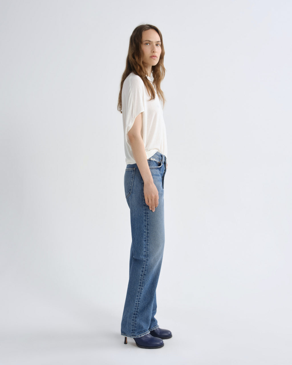Woman wearing a white top and blue jeans on a white background
