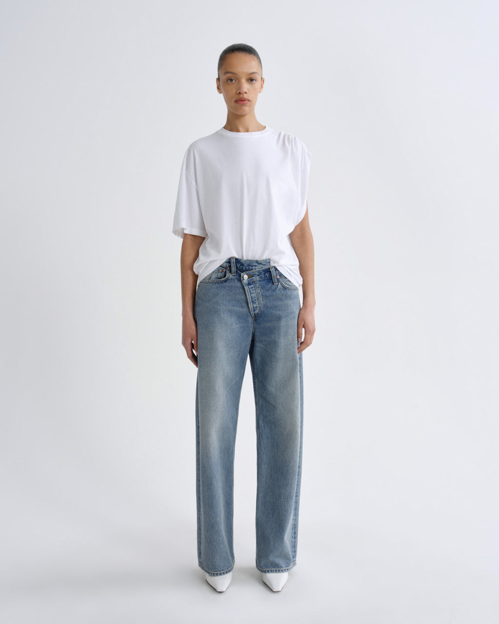 Person wearing a white t-shirt and blue jeans on a white background