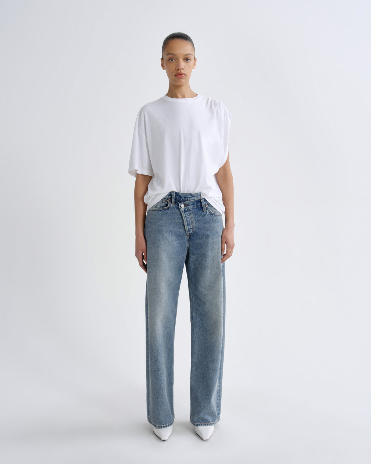 Person wearing a white t-shirt and blue jeans on a white background