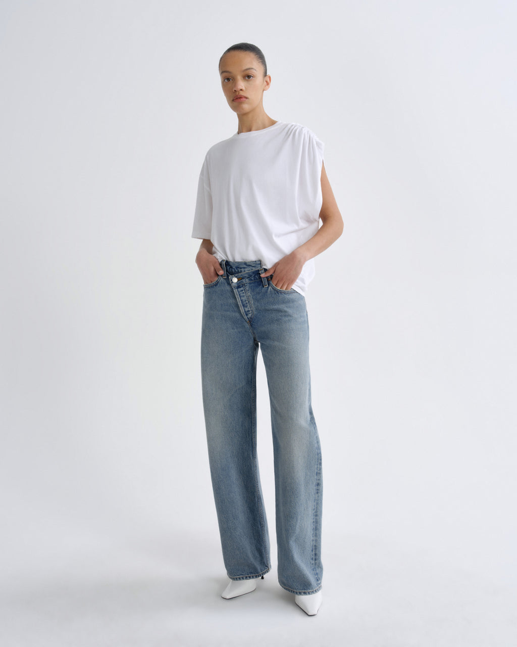 Person wearing a white t-shirt and blue jeans on a plain background